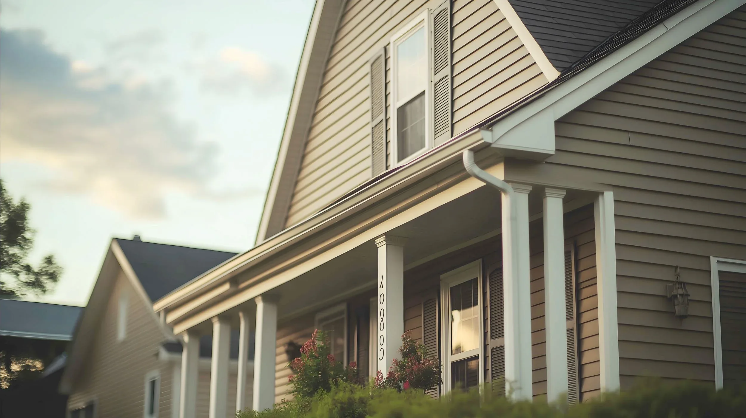 Two-story home with grey siding at sunset